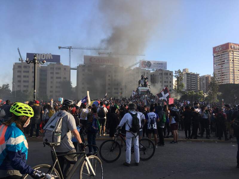 Manifestantes en Plaza Dignidad y humo
